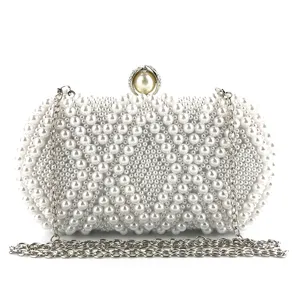 Detailed view of white pearl evening clutch bag with metal chain and rhinestone clasp.