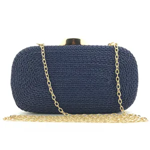 Detailed view of dark blue woven evening clutch bag with gold chain strap for women.