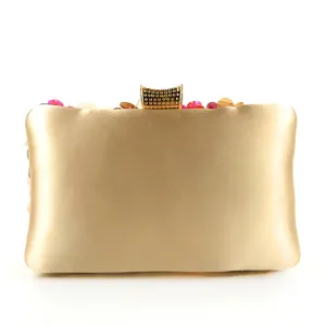 Gold satin evening clutch detail, beaded flower embellishment, elegant metallic clasp.