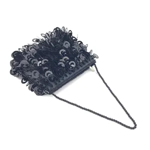 Détail de gros plan du sac de soirée noir à sequins avec bandoulière de perles.