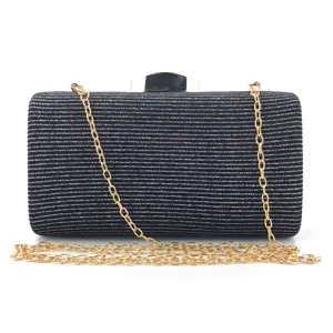 Elegant black glitter evening clutch bag detail showing sparkling fabric and gold chain strap.