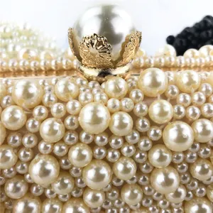 Detailopname van een luxe handgemaakte avondtas met parels en een elegante gouden sluiting.