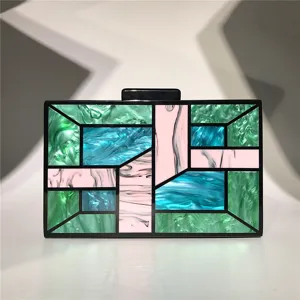 Détail de pochette géométrique en acrylique avec motif de mosaïque unique et cadre noir élégant.