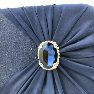 Elegant deep blue evening clutch detail shot featuring pleated satin and a large rhinestone centerpiece.