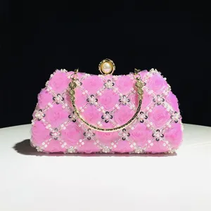 Close-up detail of the pink handmade floral beaded evening clutch bag with gold handle and pearl.
