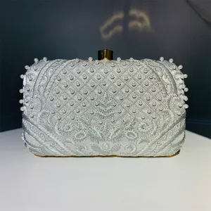 Elegante bolso de noche bordado en plata con perlas hechas a mano y cierre dorado clásico.