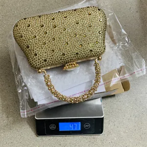 Détail de pochette de soirée en strass étincelants, sac luxueux avec poignée en métal.