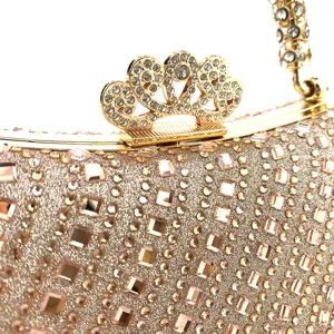 Primer plano detallado de un bolso de noche dorado con pedrería y cierre de corona brillante.