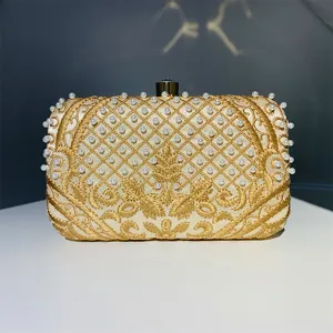 Primer plano detallado del bolso de noche bordado en oro de lujo con perlas hechas a mano.