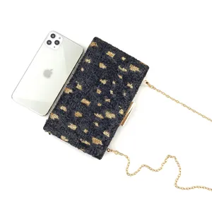Vue détail de la pochette de soirée noire et dorée à sequins avec chaîne métallique.