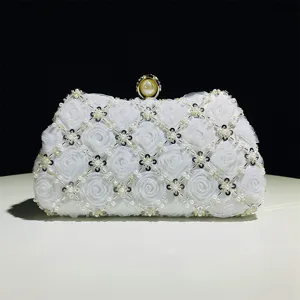 Detail view of elegant white handmade beaded evening clutch bag with fabric roses and pearl clasp.