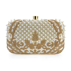 Elegante bolso de mano blanco para noche con bordado dorado y detalles de perlas finas.