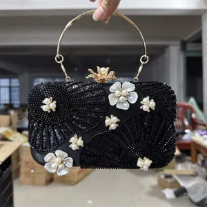 Black beaded evening clutch bag with metal round handle and elegant pearl flower decorations.