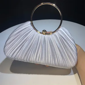 Detailed close-up shot of a white pleated satin evening clutch with a chic gold round handle.
