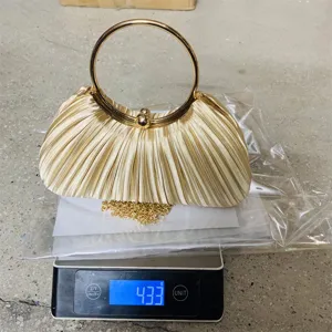 Gold satin pleated evening clutch bag with metal round handle and chain strap for party.