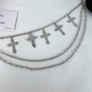 Nahaufnahme der mehrschichtigen silbernen Hose-Kette mit gotischen Kreuz-Anhängern, cooles Accessoire.