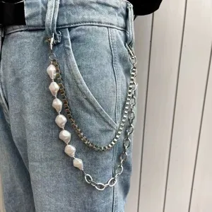 Close-up detail of multi-layer pearl and metal pants chain accessory styled on denim jeans.