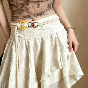 Détail de chaîne de taille tressée bohème avec perles en bois et coquillages style ethnique.