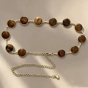 Detail shot of vintage round brown marbled metal waist chain, elegant fashion accessory.