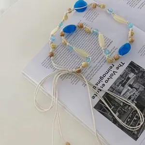 Detailed view of bohemian blue beaded braided waist chain with natural wooden beads and tassels.