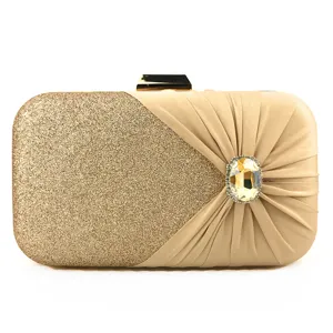 Gold glitter evening clutch bag detail showing pleated satin fabric and sparkling rhinestone buckle.