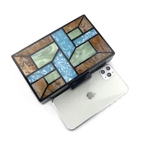 Détail de pochette de soirée géométrique en acrylique, sac à main rigide motif marbré.