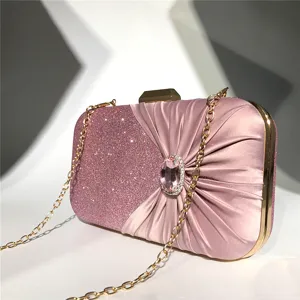 Detailed view of women elegant evening clutch bag with sparkling glitter and ruched satin design.