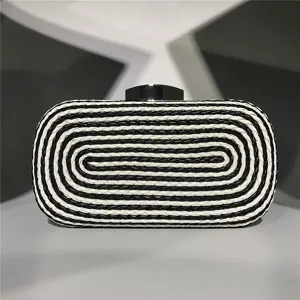 Detailed view of the black and white woven clutch bag with metal clasp for evening events.