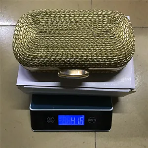 Detail view of the elegant gold woven women clutch evening bag showing product weight on scale.