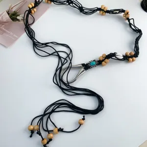 Détail de ceinture cordon tressée noire bohème avec perles en bois et fermoir turquoise.