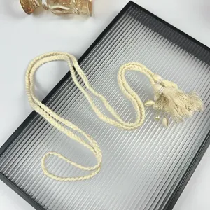 Close up of bohemian beige braided rope waist belt featuring tassel pearl shell pendants.