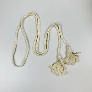 Close-up of bohemian braided rope belt detail featuring elegant pearl and shell tassel pendants.