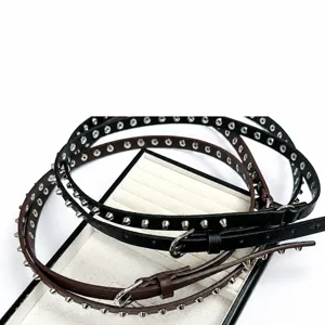 Detailed view of punk style thin studded leather belts in black and brown with metal buckles.