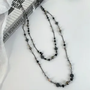 Close-up detail of double layered bohemian waist chain with dark beads and metal flowers.
