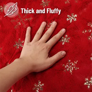 Close-up detail of plush red Christmas tree skirt showing thick fluffy fabric with gold sequins.