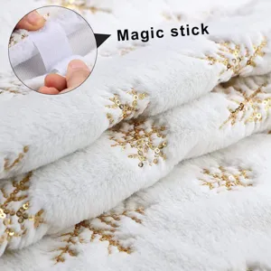 Vue détaillée de la jupe de sapin de Noël en peluche blanche avec des flocons de neige dorés et velcro.