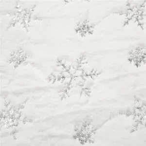 Détail de tissu de jupe de sapin de Noël en peluche blanche avec des flocons de neige argentés.