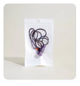 Nahaufnahme eines violetten Kristall-Kuerbis-Anhaengers in einem transparenten Beutel.