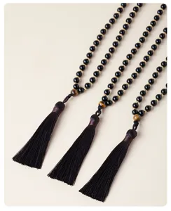 Gros plan détaillé de chaînes de pull en perles d'obsidienne noire avec des pompons élégants.