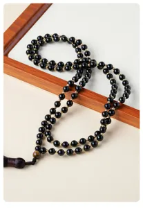 Détail de collier de perles en obsidienne, perles noires avec espaceur doré et pendentif.
