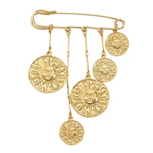 Detailansicht einer goldenen Vintage-Brosche mit Sonnenmasken-Anhängern und Sicherheitsnadel