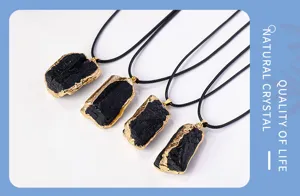 Detail view of natural black tourmaline raw stone pendant with gold-plated edge and cord.