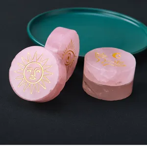 Natural rose quartz crystal disc with gold engraved mystical sun, eye and moon patterns.
