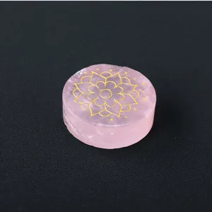 Detailed close-up of natural rose quartz crystal disc with gold laser engraved lotus pattern.