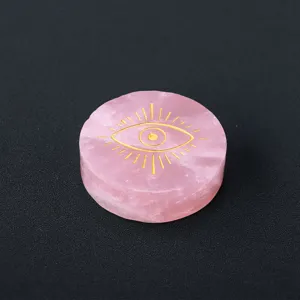 Natural rose quartz crystal disc with golden laser engraved mystical eye pattern for decor.