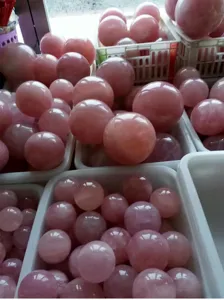 Detailed view of natural rose quartz crystal spheres displayed in wholesale warehouse bins.