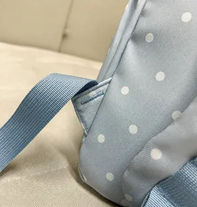 Light blue polka dot school backpack detail shot, cute casual daypack with reinforced strap.