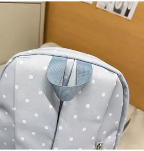 Detailed close-up view of light blue polka dot backpack top handle design for students