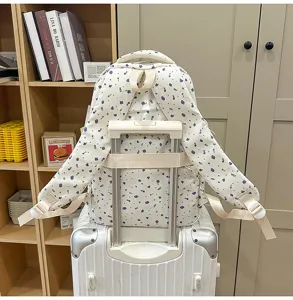 Detailed view of white floral school backpack on suitcase, casual style book bag.