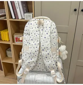 Detailed view of the white floral backpack with cute bear pendant, showing straps and scene.